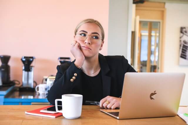 A woman bored in front of a computer.