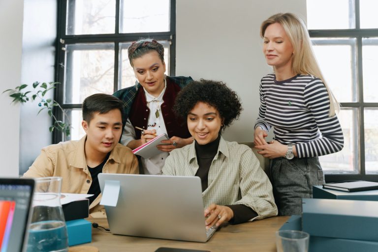 A group of co-workers around one laptop.